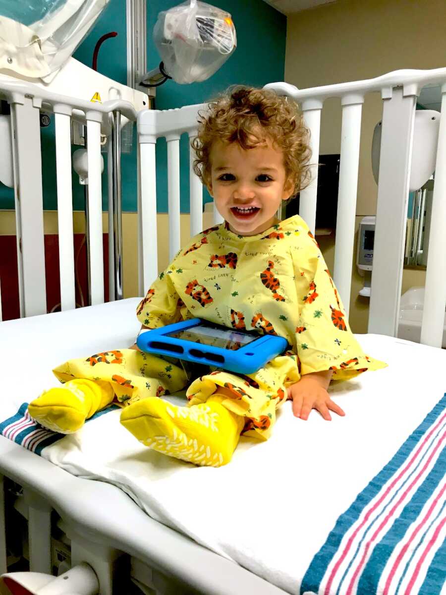 young boy sits in the hospital in a crib