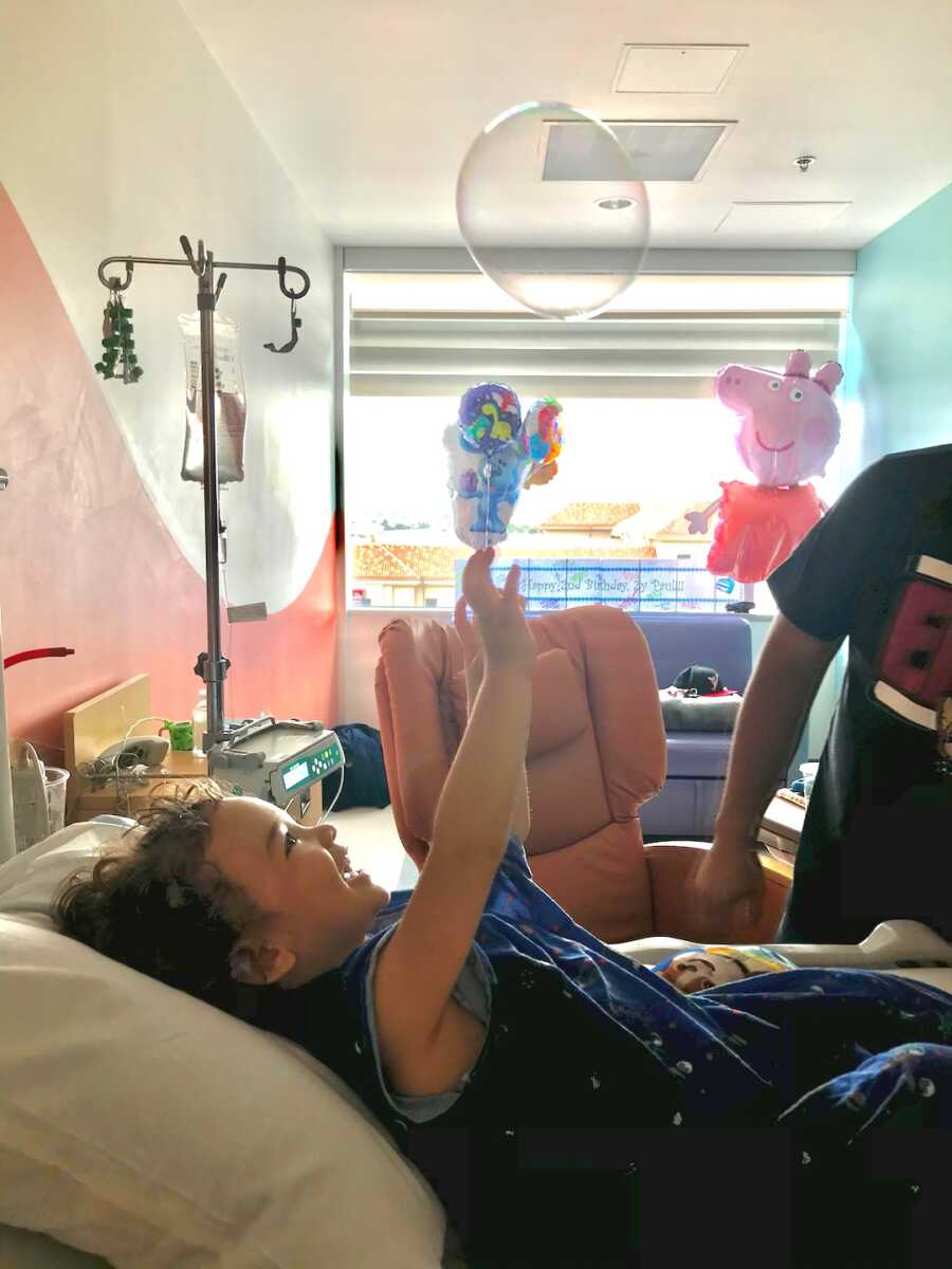 boy with childhood cancer plays with bubbles while in the hospital
