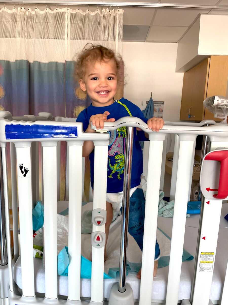 boy stands in the hospital with a big smile and a cast on his leg