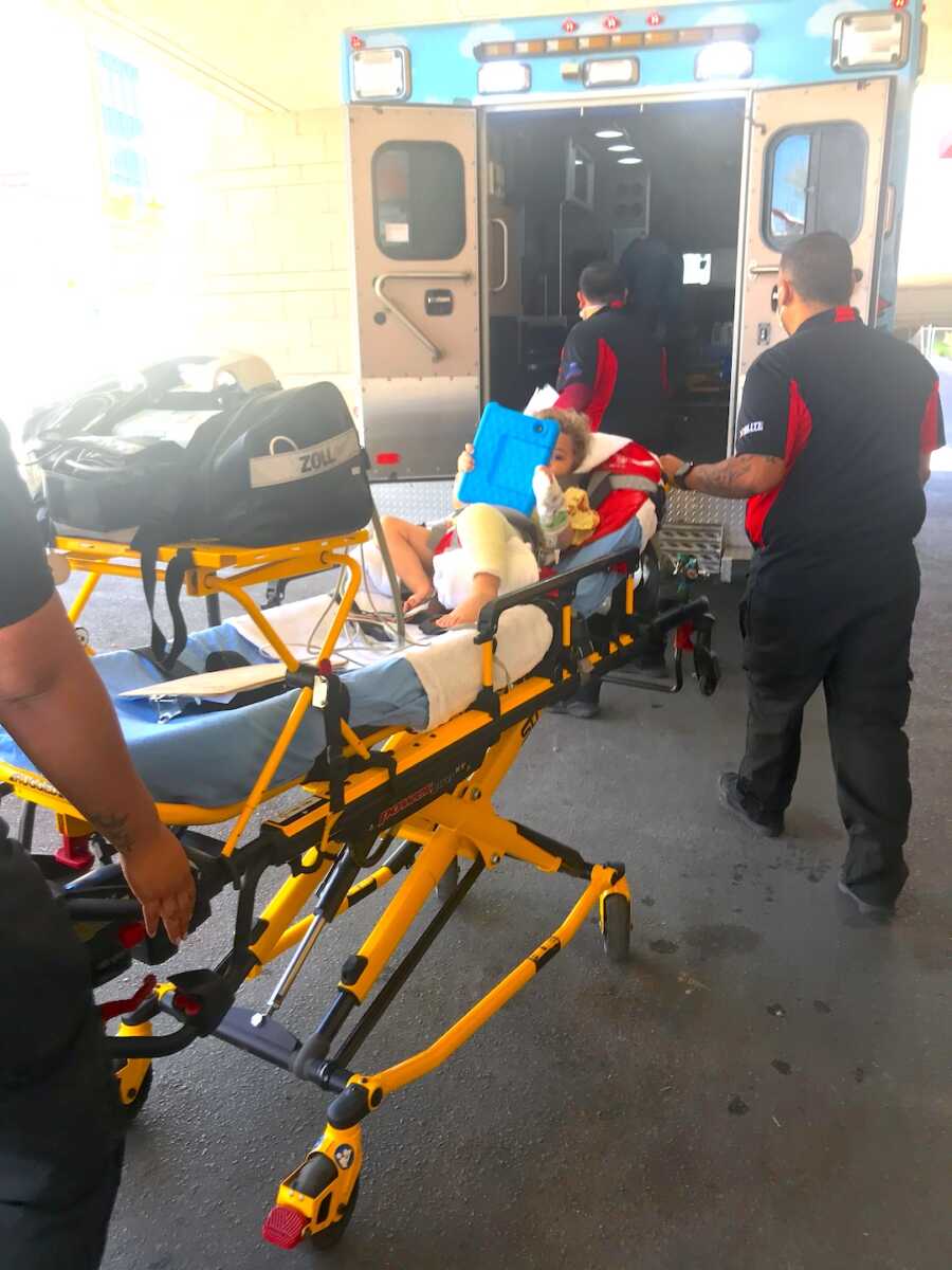 boy gets loaded into an ambulance to go to the hospital for a broken leg
