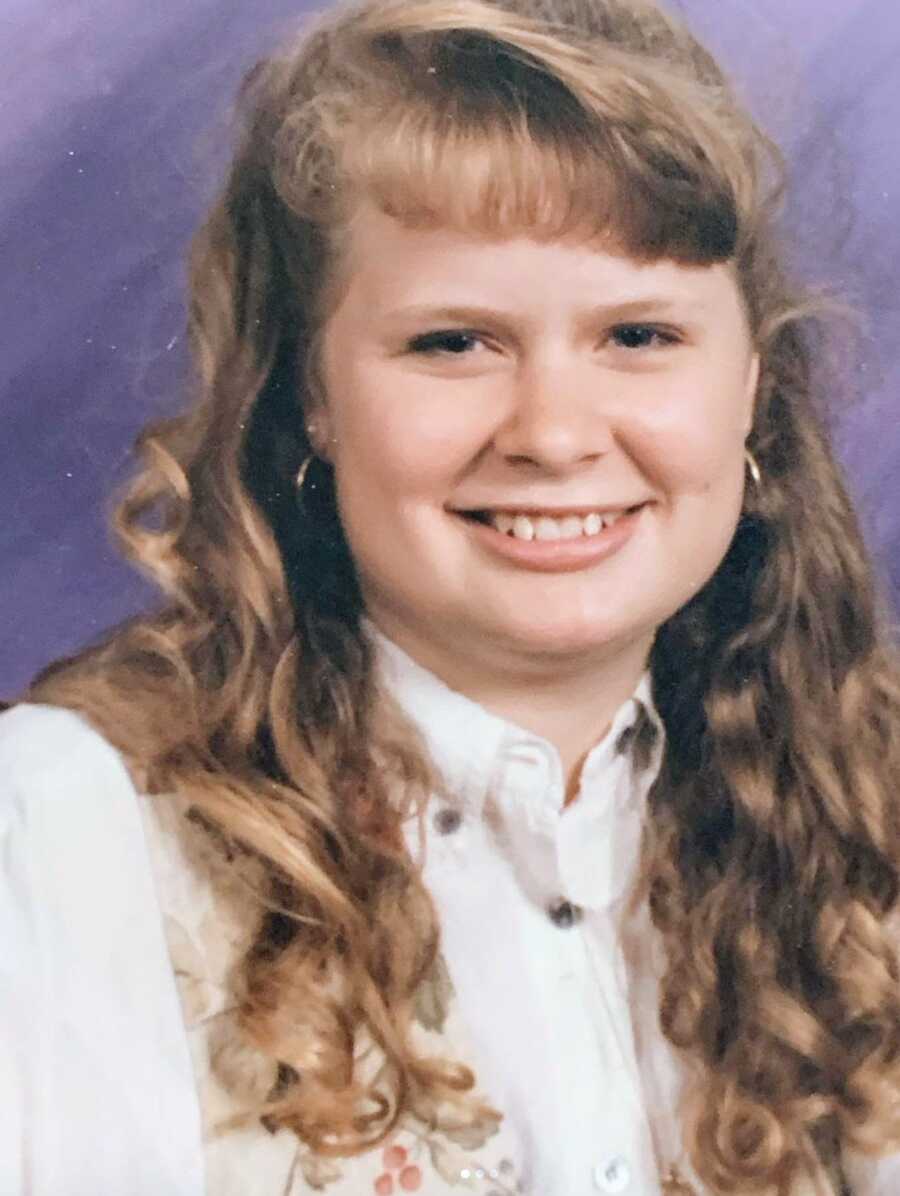 A young woman with long brown hair wearing a white shirt