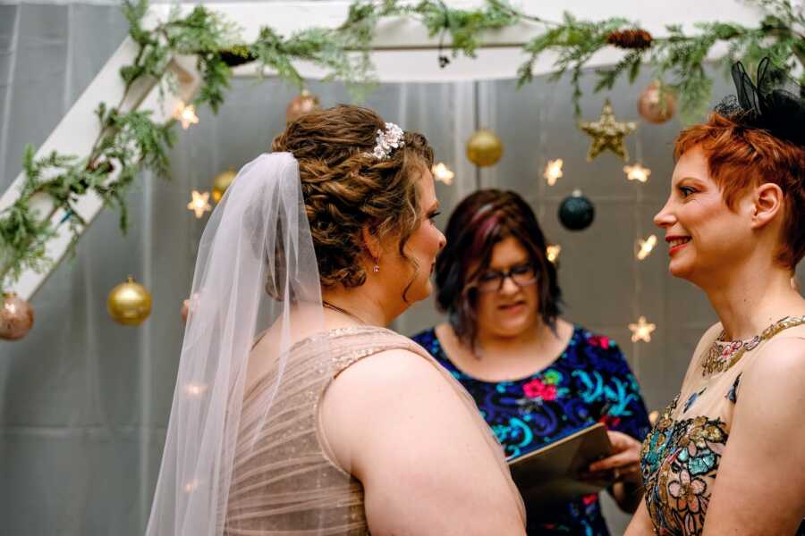 A lesbian couple stand at an altar decorated with stars and branches on their wedding day