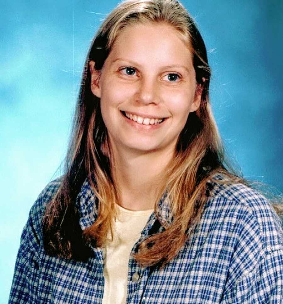 A young woman with long blonde hair wearing a blue plaid shirt
