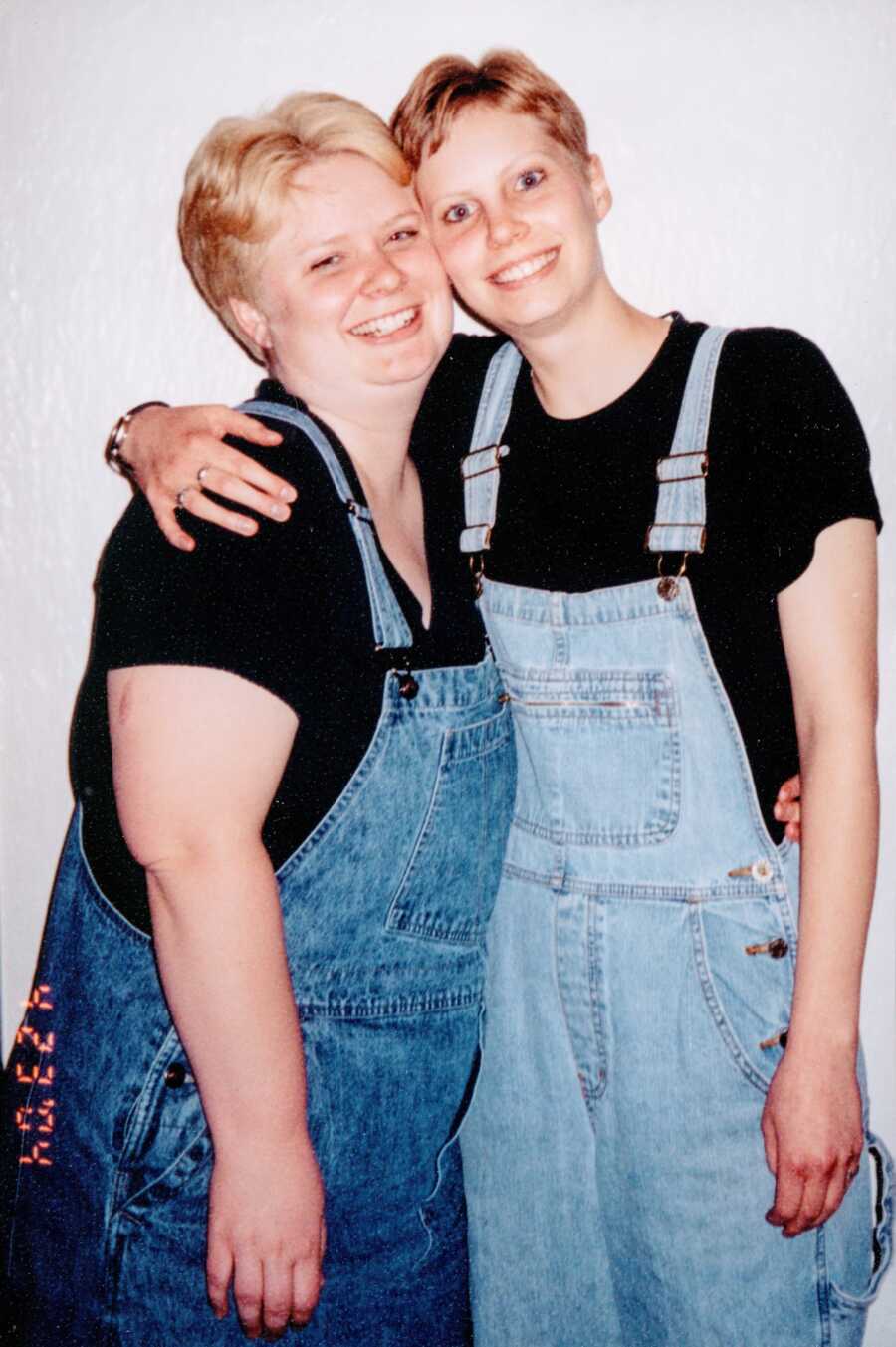 A lesbian couple wearing matching overalls and black T-shirts