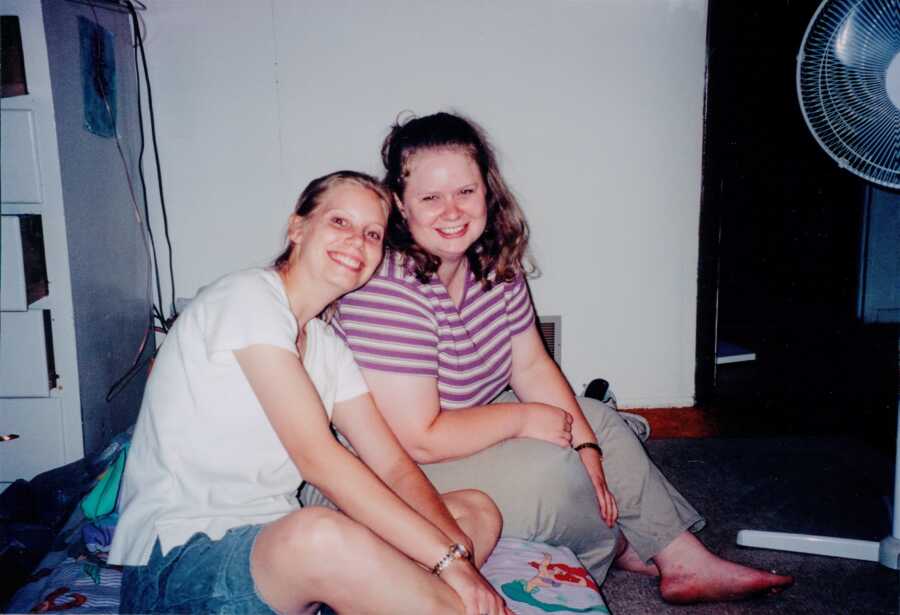 A pair of women sit next to each other on the floor