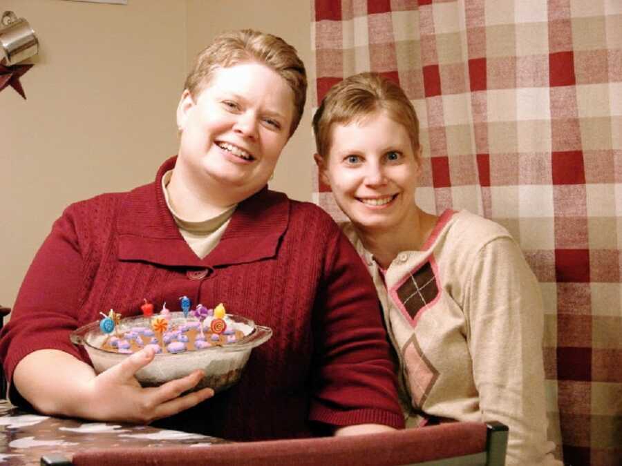 A couple hold a desert while sitting next to each other at a dining table