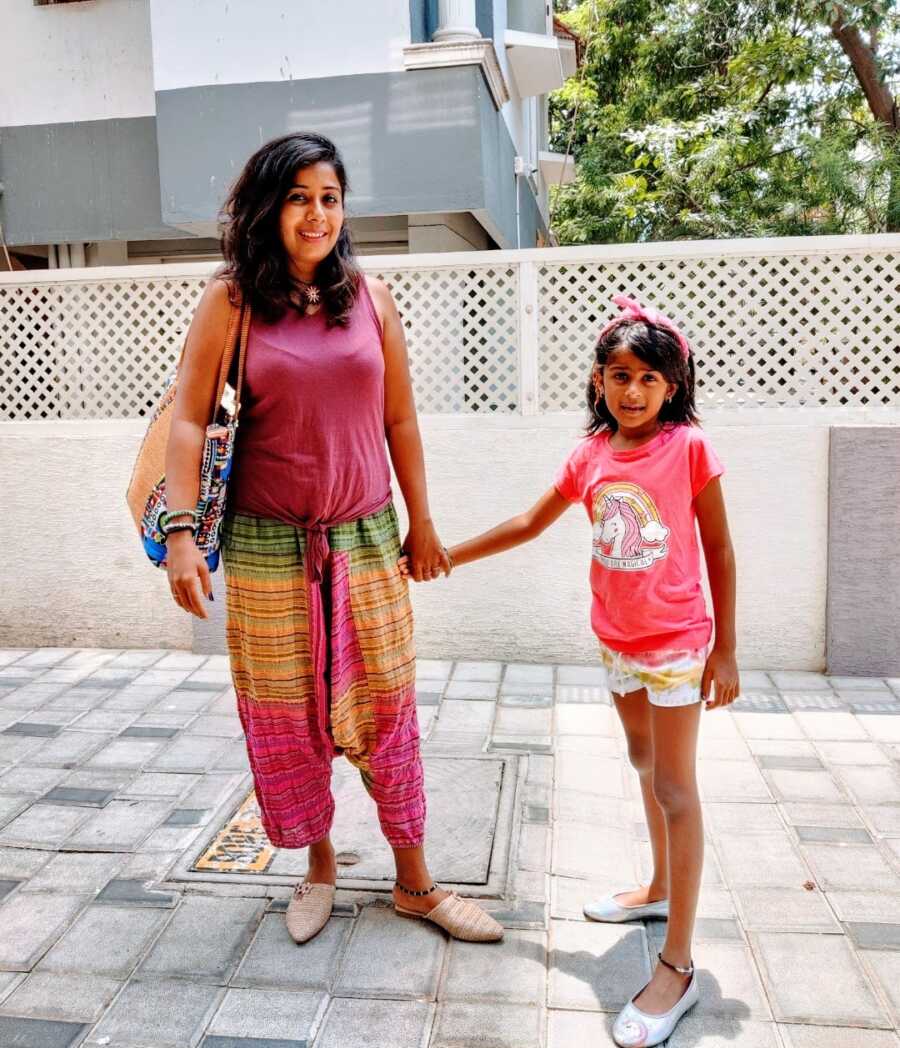 A mom holding her daughter's hand outside