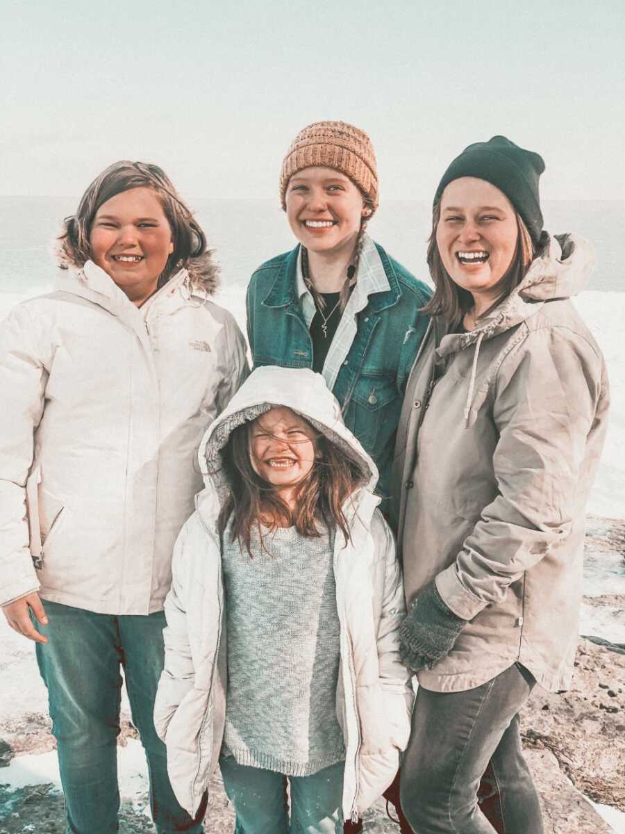 Birth mother, birth daughter, and half sisters take picture in winter coats.