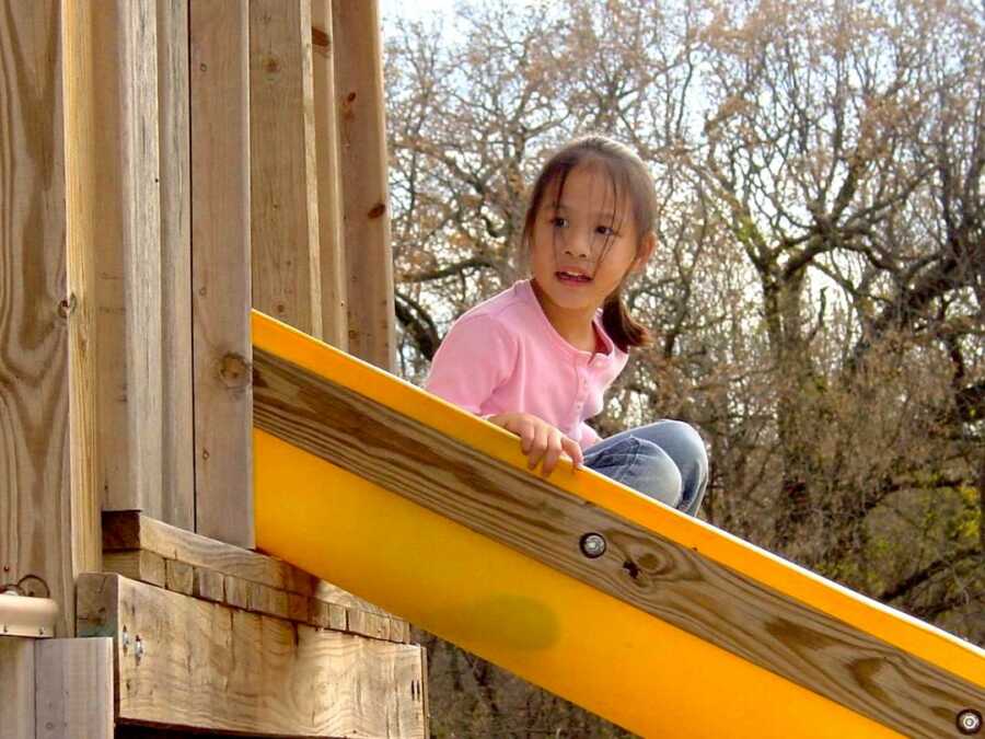 adoptee slides down a slide on a play set