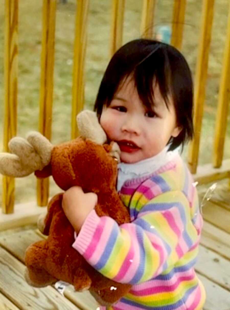 young adoptee sits and holds a stuffed animal