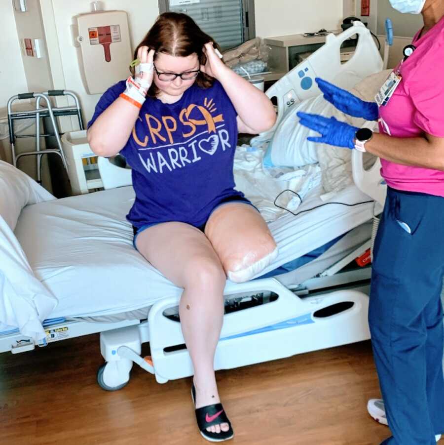 An amputee sits on the edge of a hospital bed after surgery