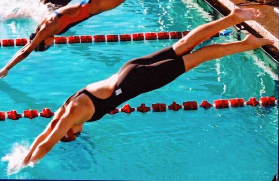 A woman jumping into a pool to begin swimming