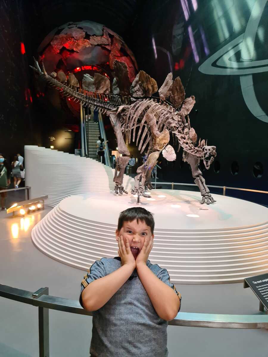 little boy in front of a dinosaur skelton 