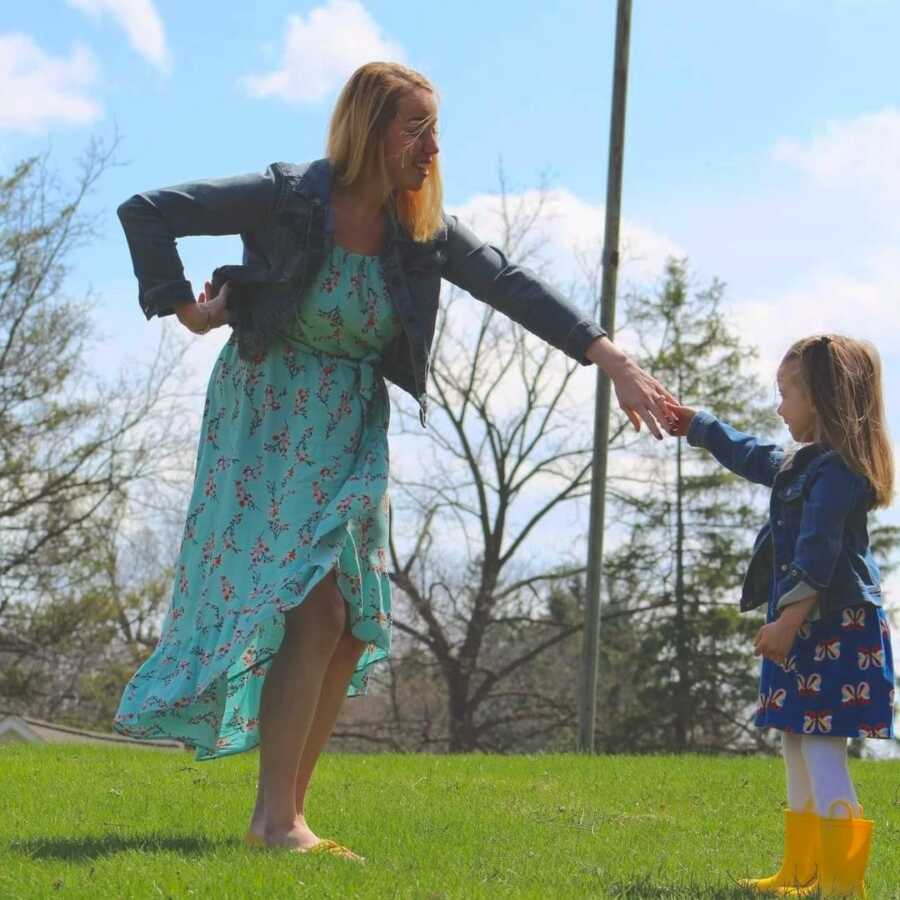 mom holds out her hand to her young daughter