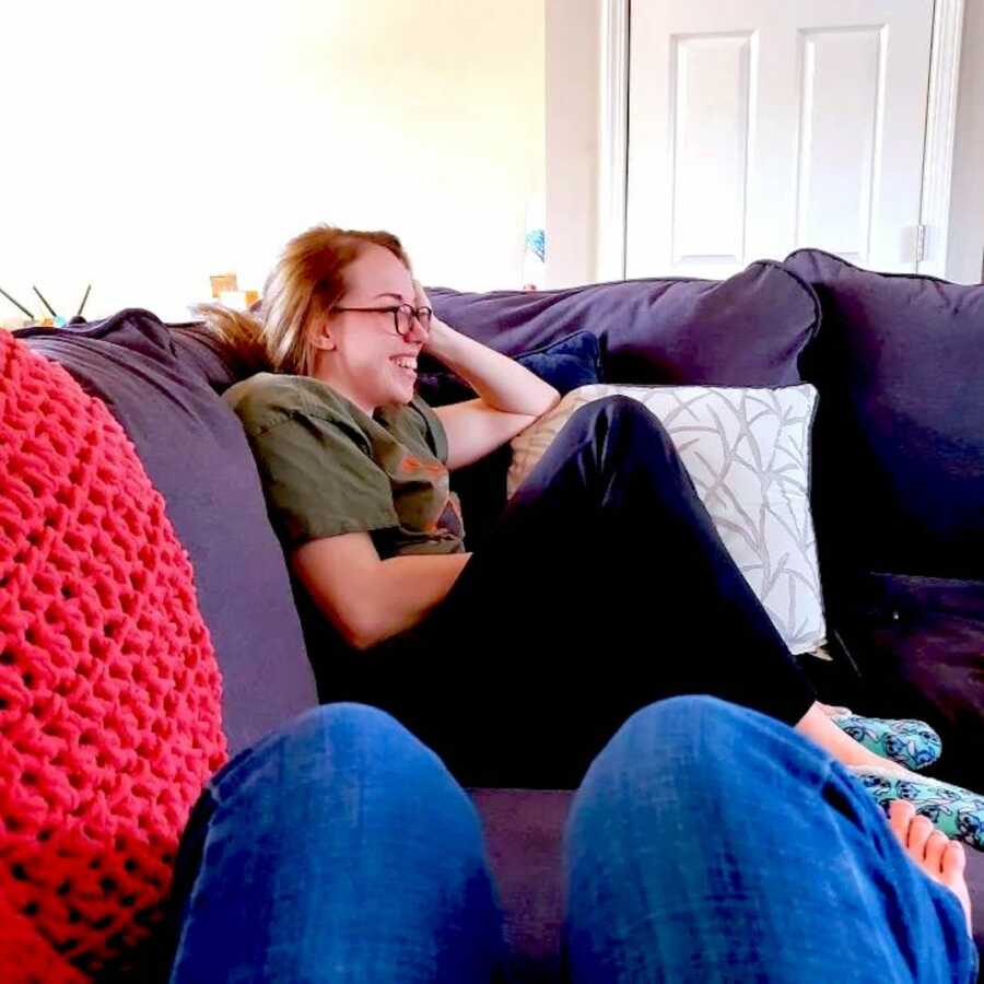 woman sits on the couch facing forward smiling