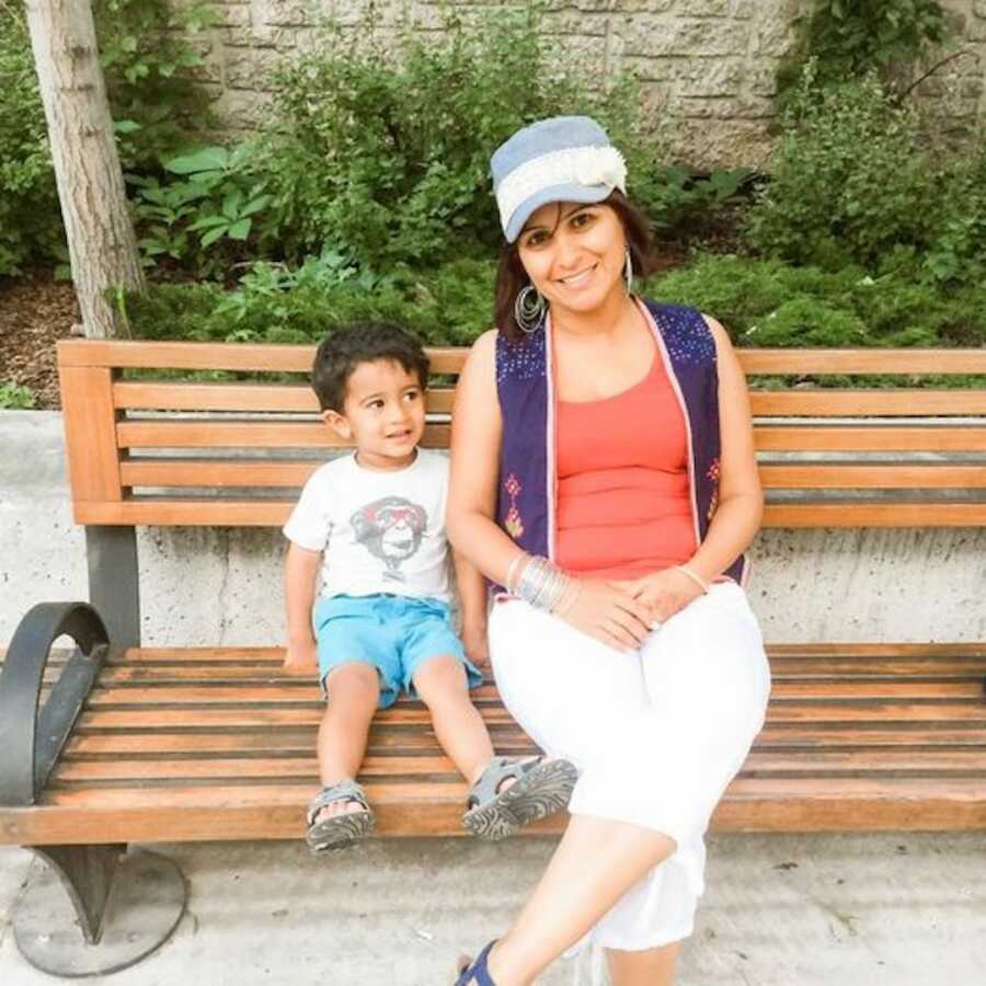 son sitting with mom on a bench smiling