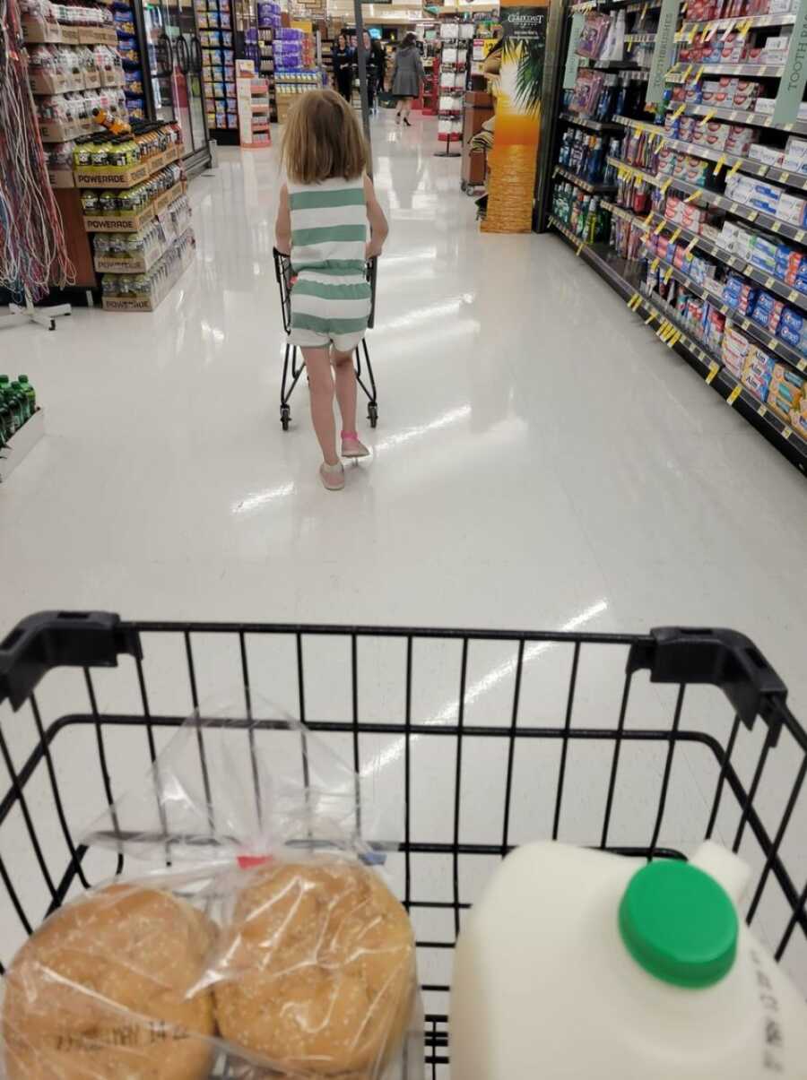 little girl walking ahead of mom in the grocery store