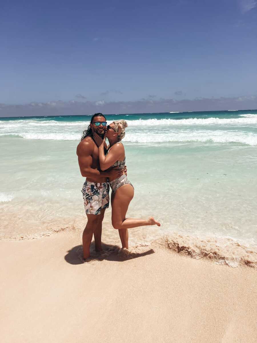couple on the beach taking a cute photo while she kisses his cheek