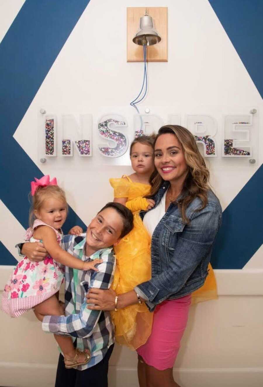 mom with children standing in front of a sign 