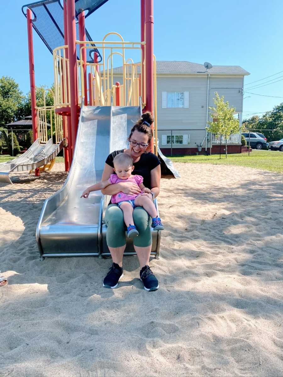 Mom and daughter go down a slide together at the park