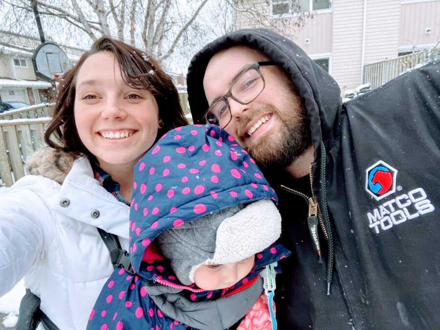 Husband and wife take a selfie in the snow with one of their children