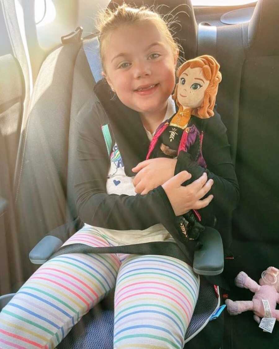 Mom takes a photo of her elementary school-aged daughter sitting in the back seat on the way to school