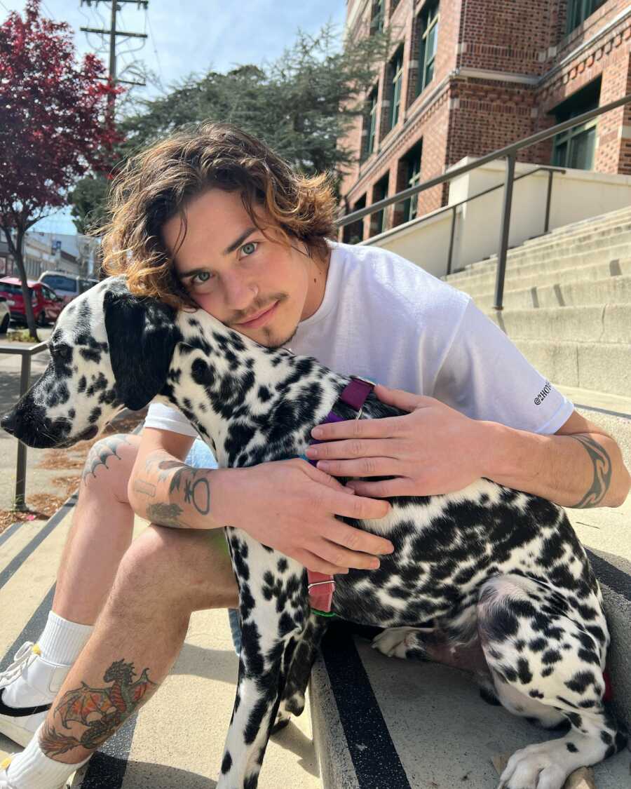non binary person hugging a dog