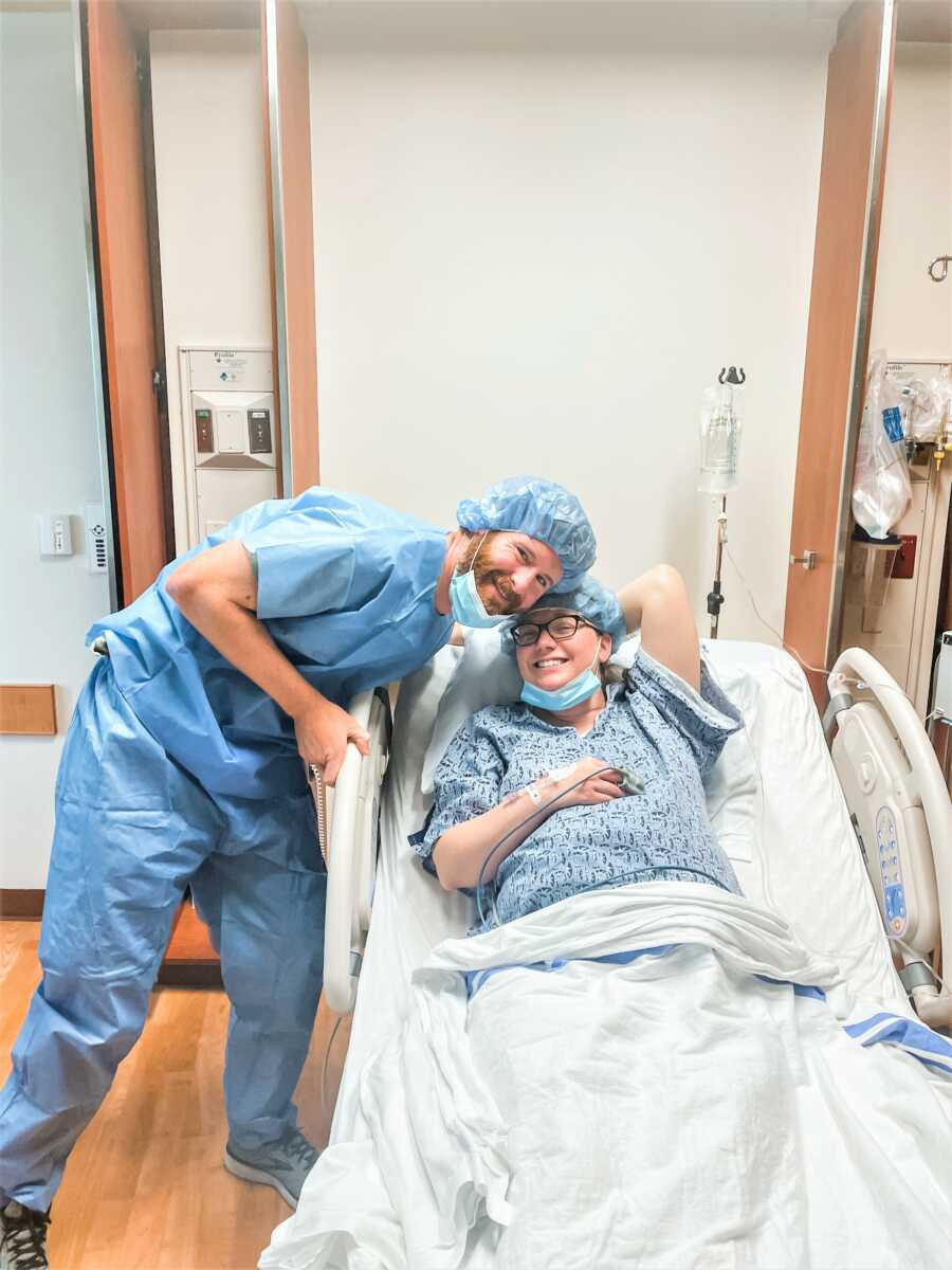 Pregnant woman laying on a hospital bed next to her husband prior to an emergency C-section