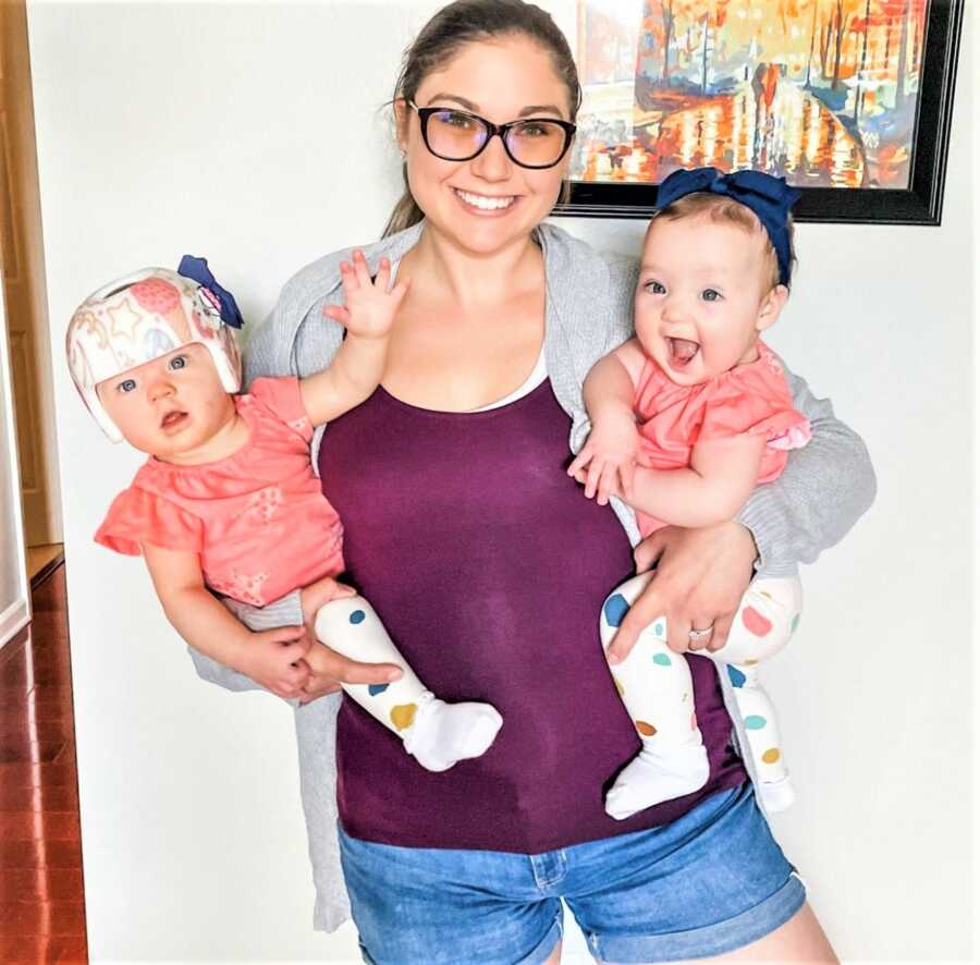 Mom holding her twins wearing matching outfits on each arm