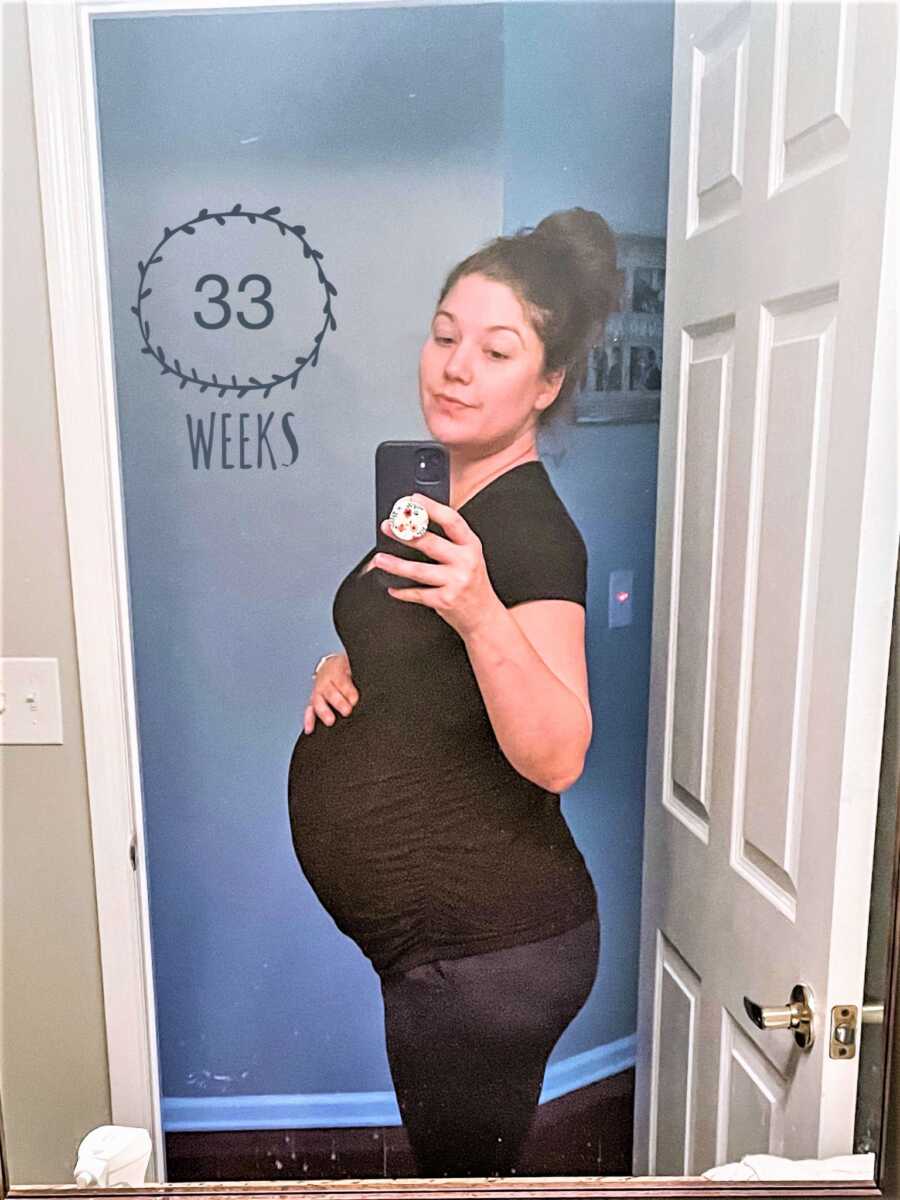 Mirror selfie of pregnant woman on her 33rd week of pregnancy