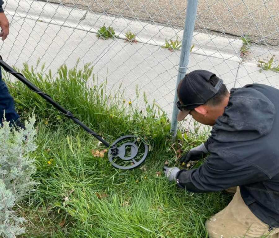 gardeners with metal detector looking for necklace