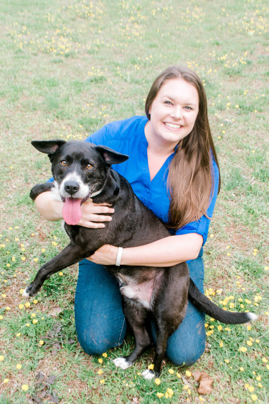 woman and her black dog sitting on the grass and smiling