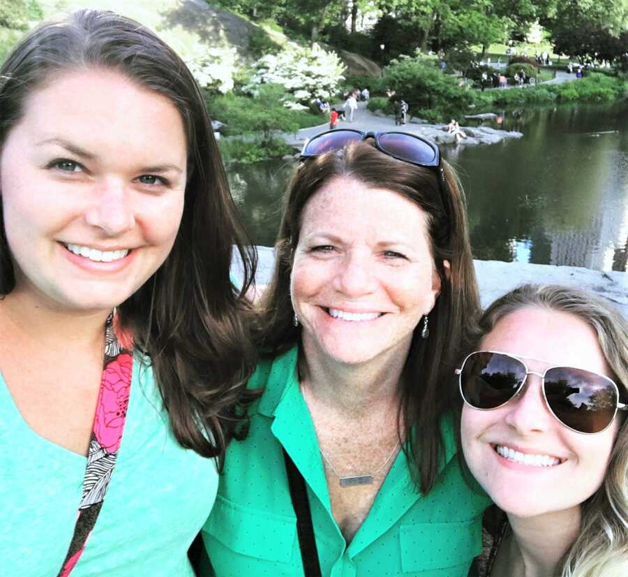 selfie on a mom with her two adult daughters wearing green t-shirts with a lake in the background 