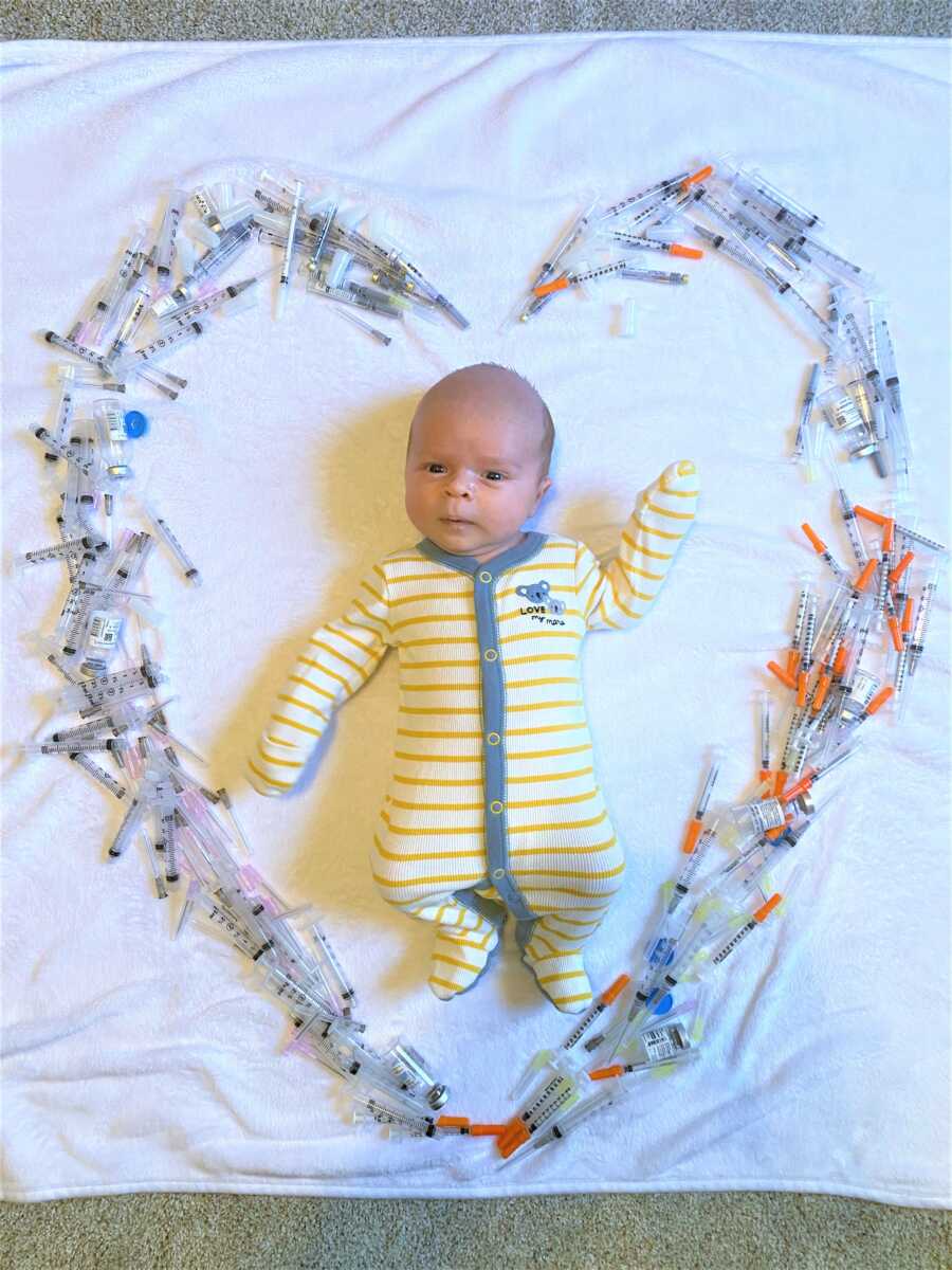 Baby conceived through IVF takes a photo with a heart made of needles surrounding him