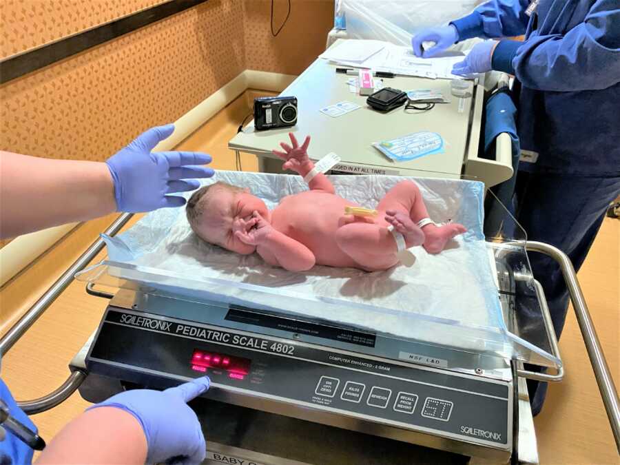 newborn baby boy being weighted at the hospital right after delivery