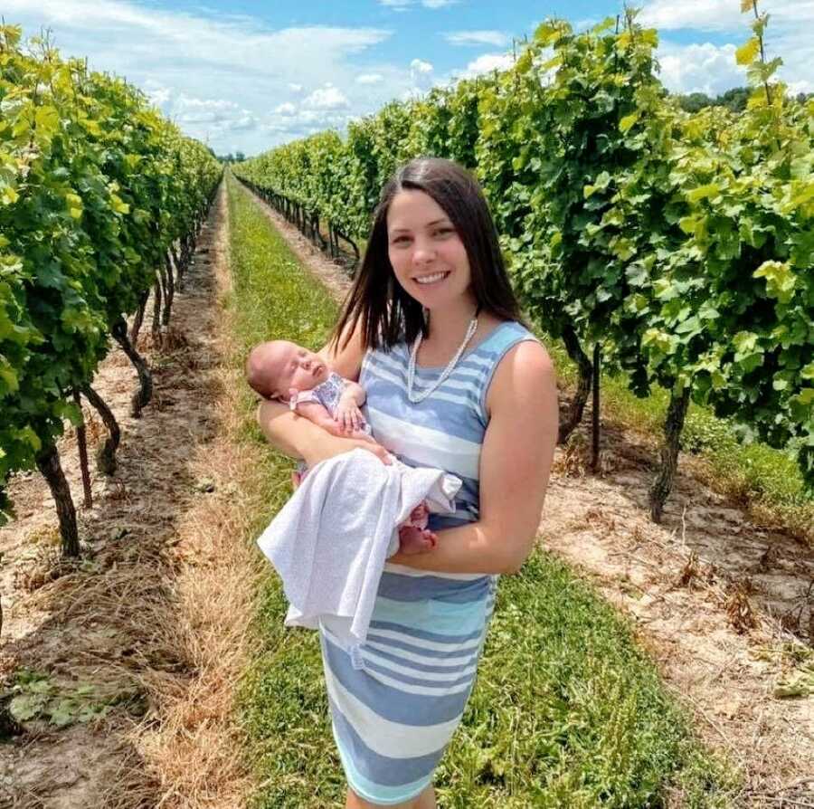Mom holds her newborn daughter during a wine tour at a vineyard