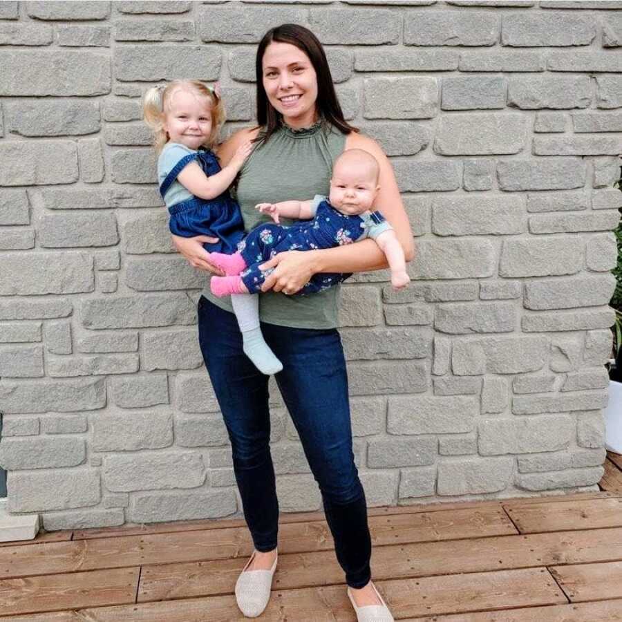 Mom holds her two daughters wearing matching denim outfits