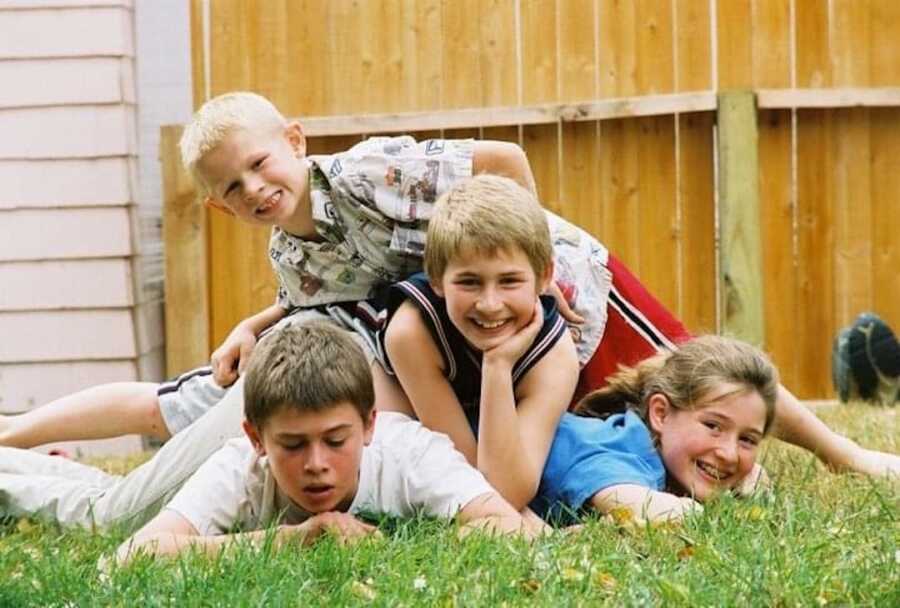 young boys and a girl laying on top of one another 