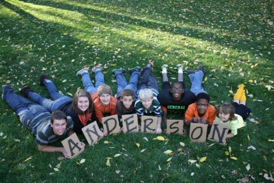 children laying on stomach in grass holding a letter