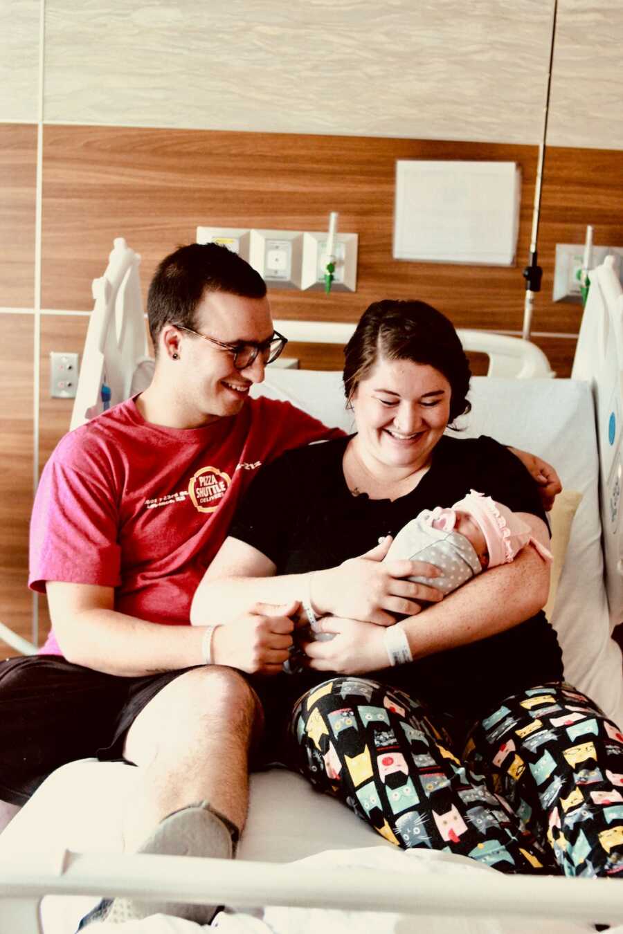 man and woman laying in hospital bed with baby 
