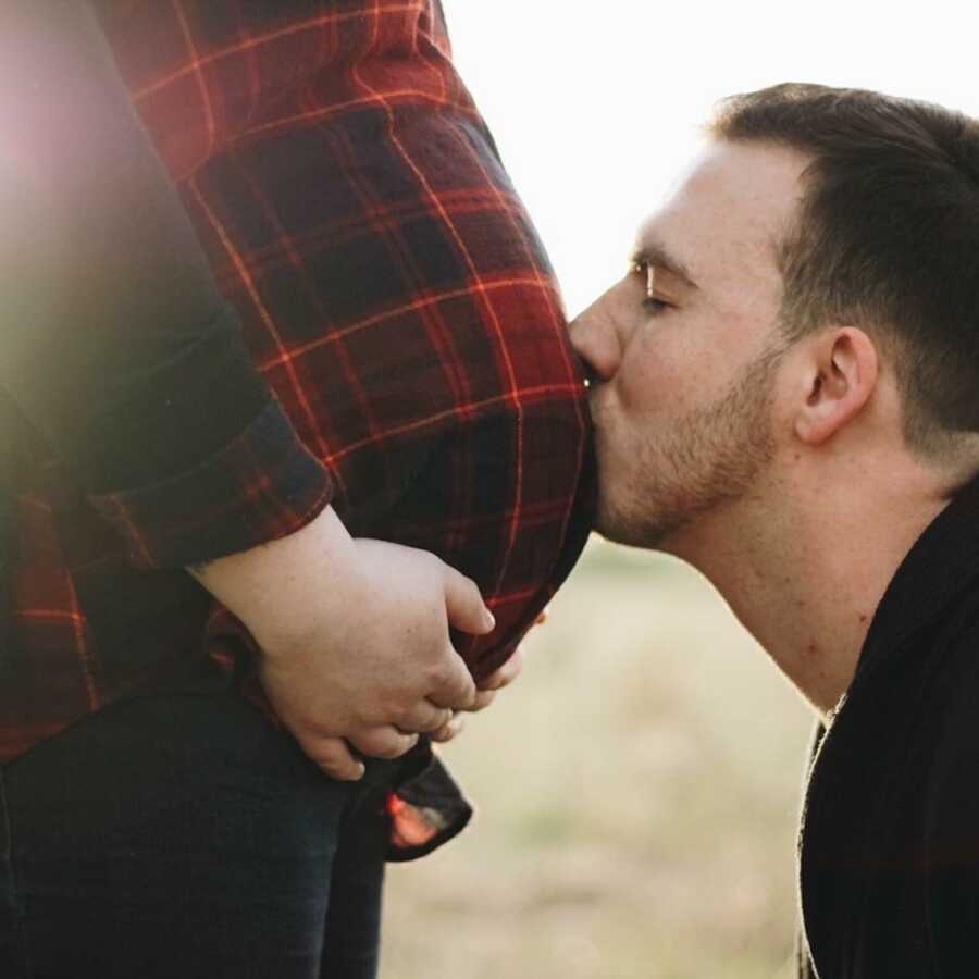man kissing a pregnant woman's stomach 