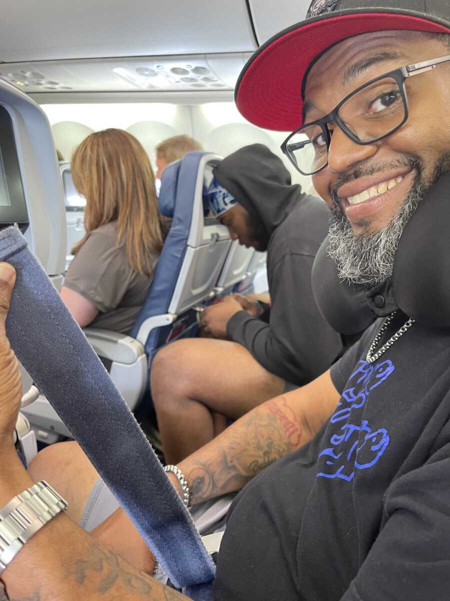 man on airplane lifting seat belt