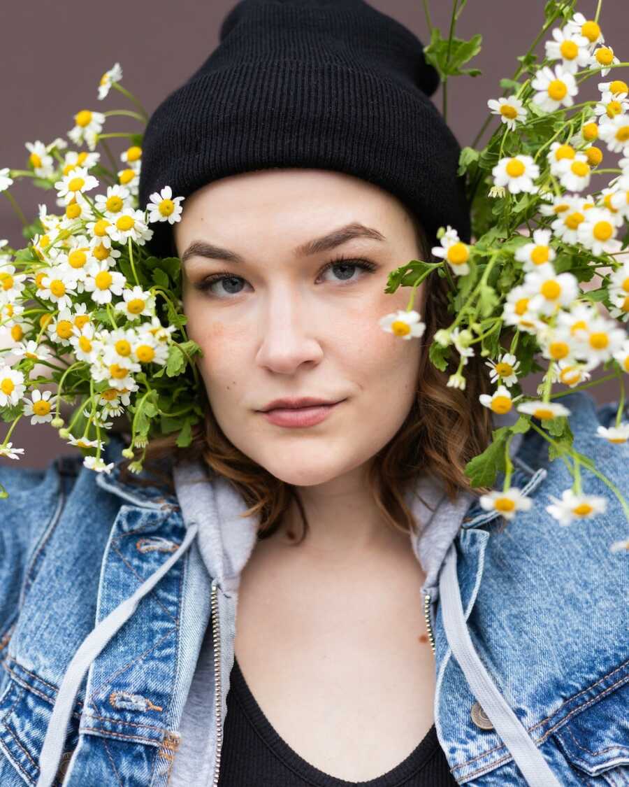 non binary person with flowers by their face