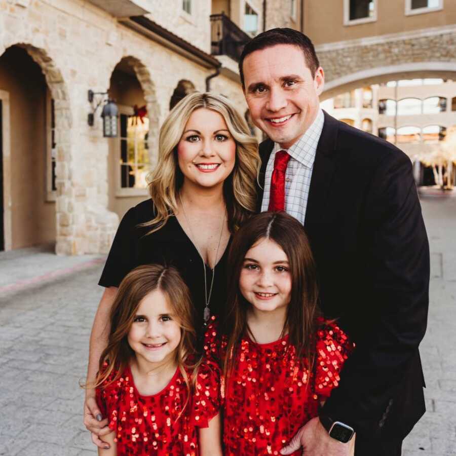 Professionally taken family portrait of mom, dad and two daughters wearing formal outfits