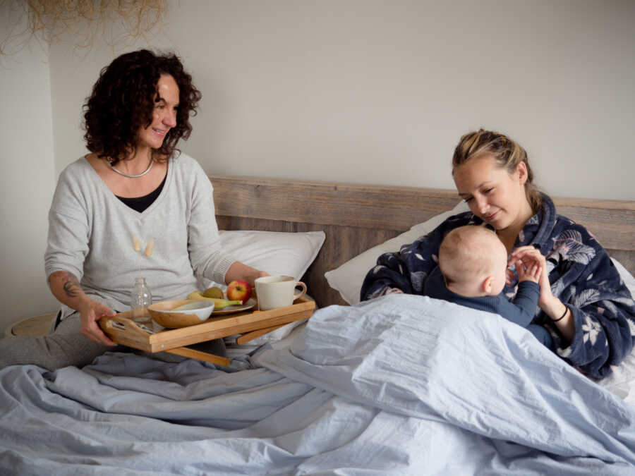 woman helping new mom by bringing her breakfast in bed