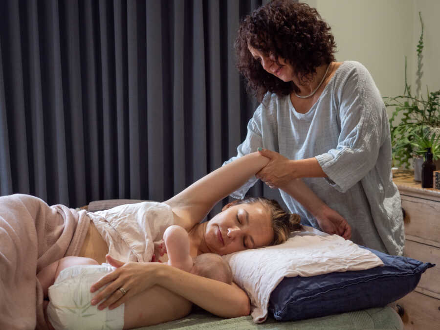 woman giving new mom a massage to help her postpartum