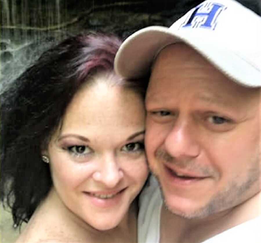 selfie from a high angle of a woman and a man who is wearing a white baseball hat