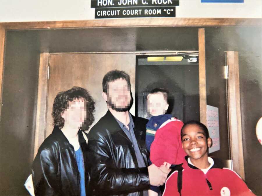 Young black boy next to his white adoptive parents and sibling