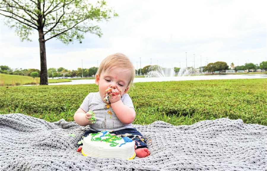 baby boy sitting unassisted and eating birthday cake on his 1st birthday 