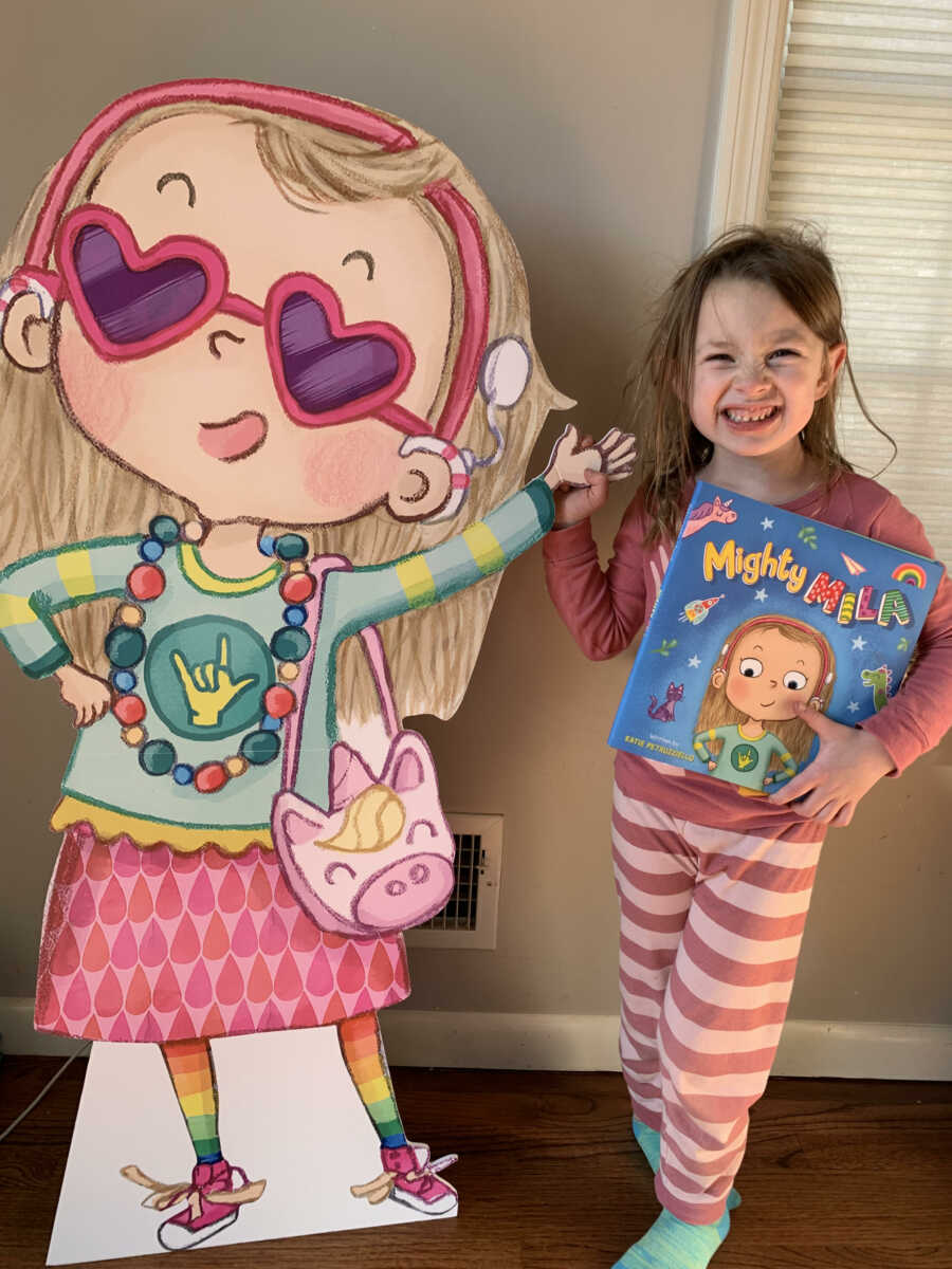 little girl standing next to the drawing of her